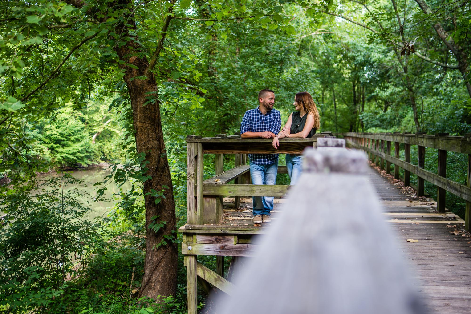 Couple standing on bridge over pond